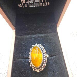 sterling silver ring featuring a large, oval butterscotch amber